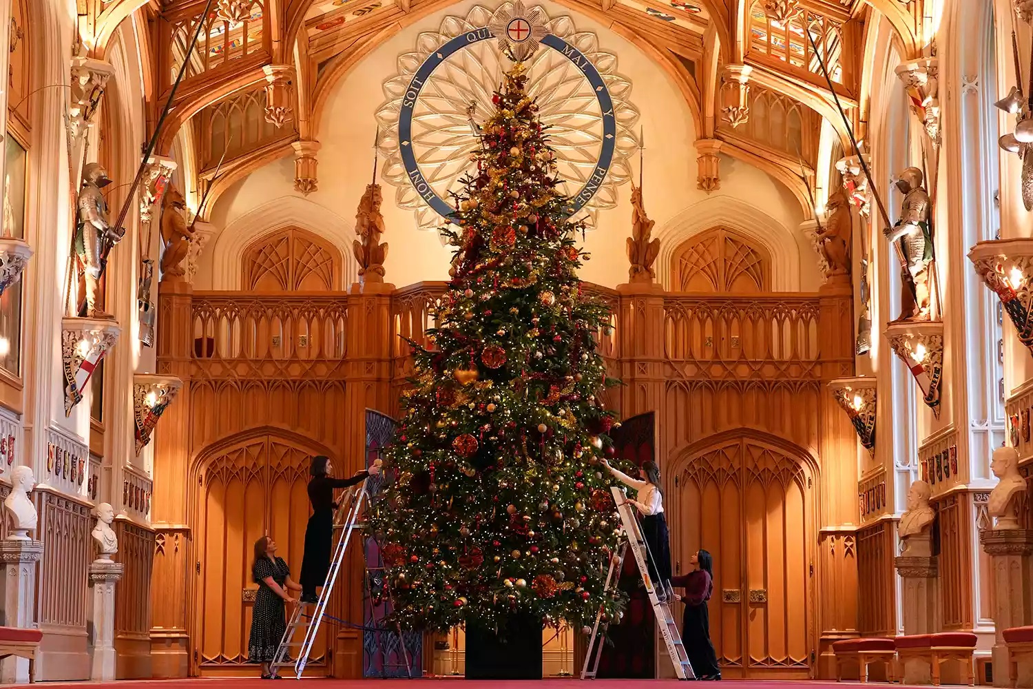 Royal Collection Trust staff add the finishing touches to a Christmas tree in St George's Hall, during a photo call for Christmas decorations at Windsor Castle photo Andrew Matthews- PA Images via Getty